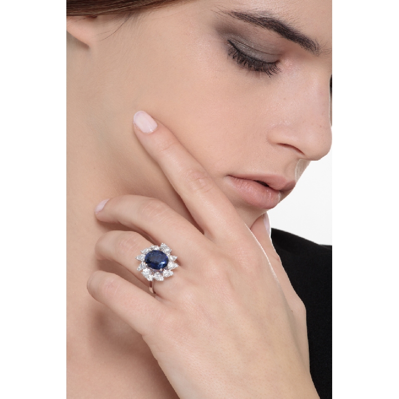 Anillo halo en oro blanco de 18k con un zafiro azul talla ovalada y diamantes